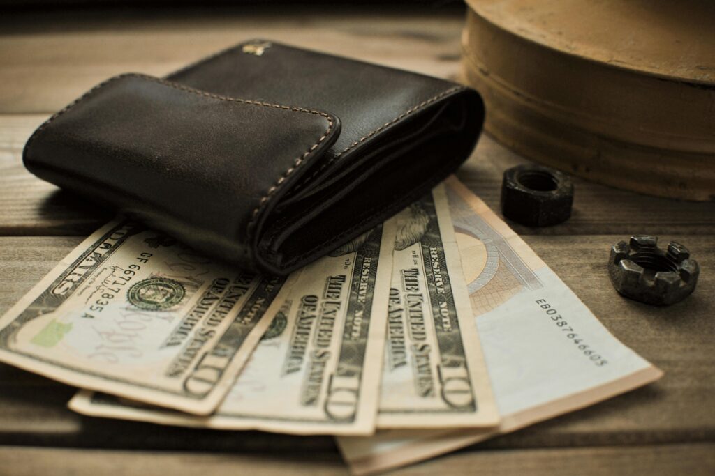 Close-up view of a leather wallet with US dollar bills on a wooden table.