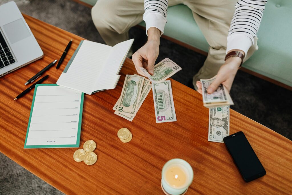 High angle view of hands handling money on a wooden table with digital currency coins.