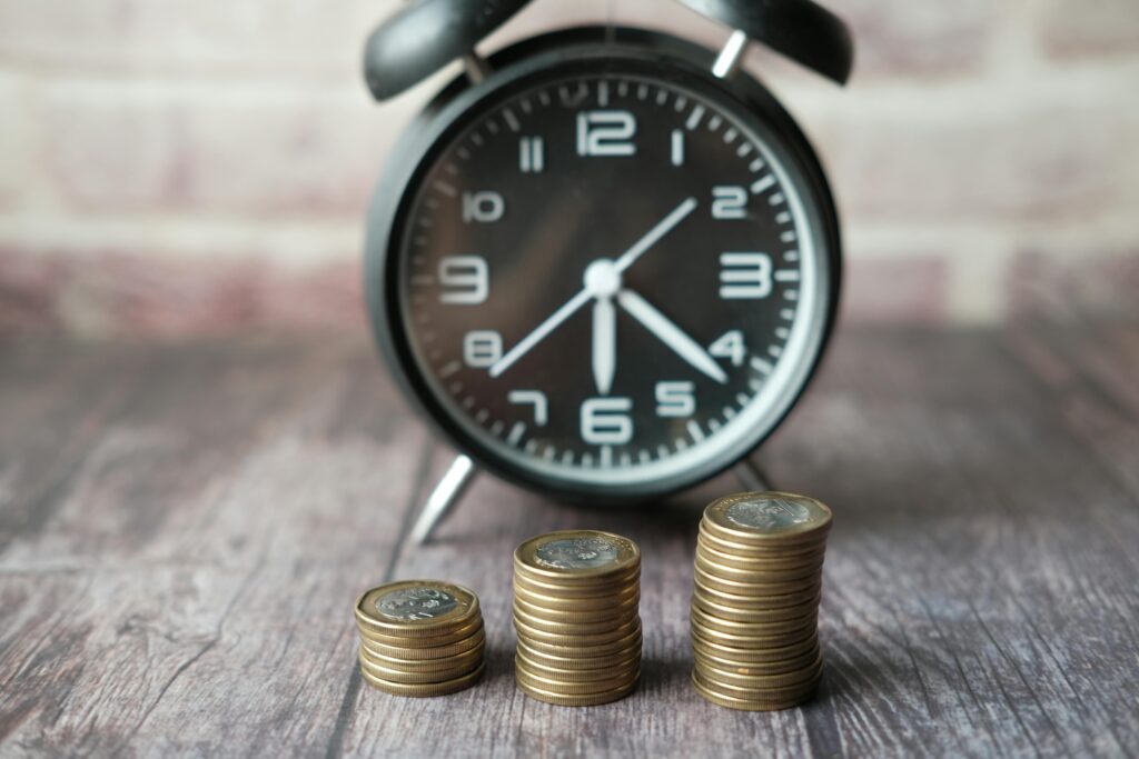 Stacked coins and a classic alarm clock symbolize the value of time and money.
