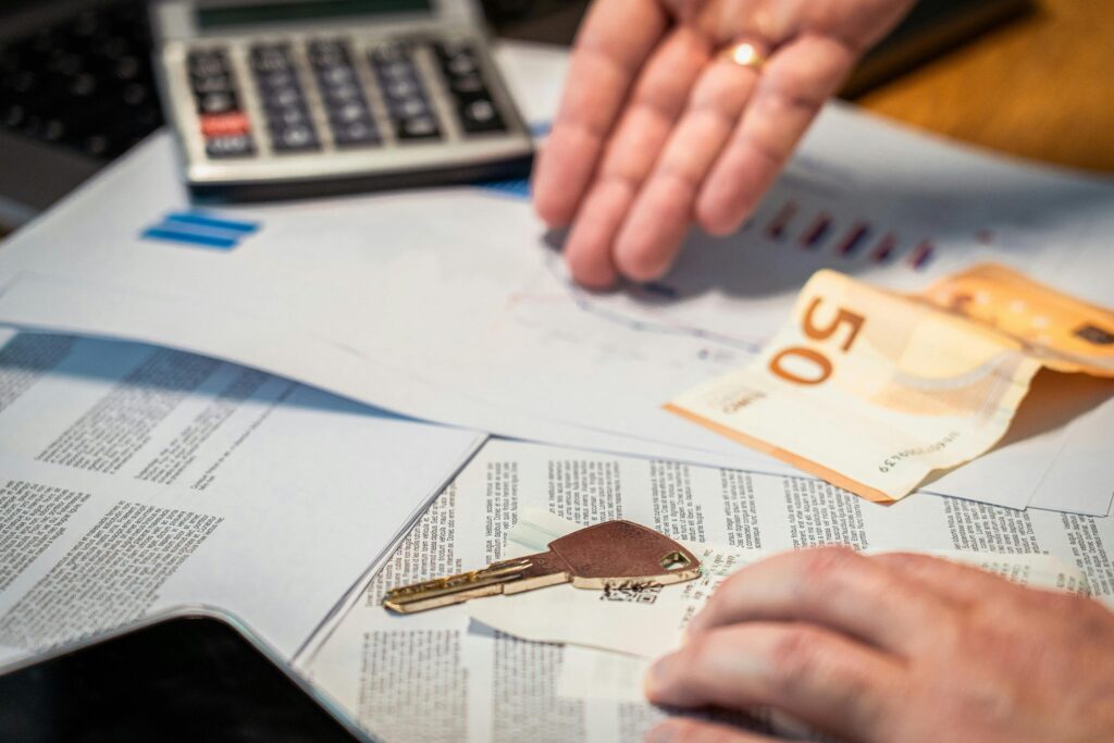 Hands examining financial documents, a 50 euro note, and a key, suggesting investment or real estate themes.
