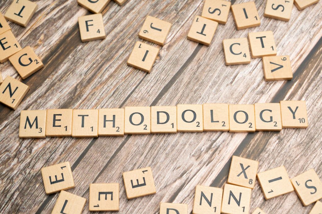 Wooden letter tiles spelling 'methodology' on a textured wooden surface, emphasizing research.