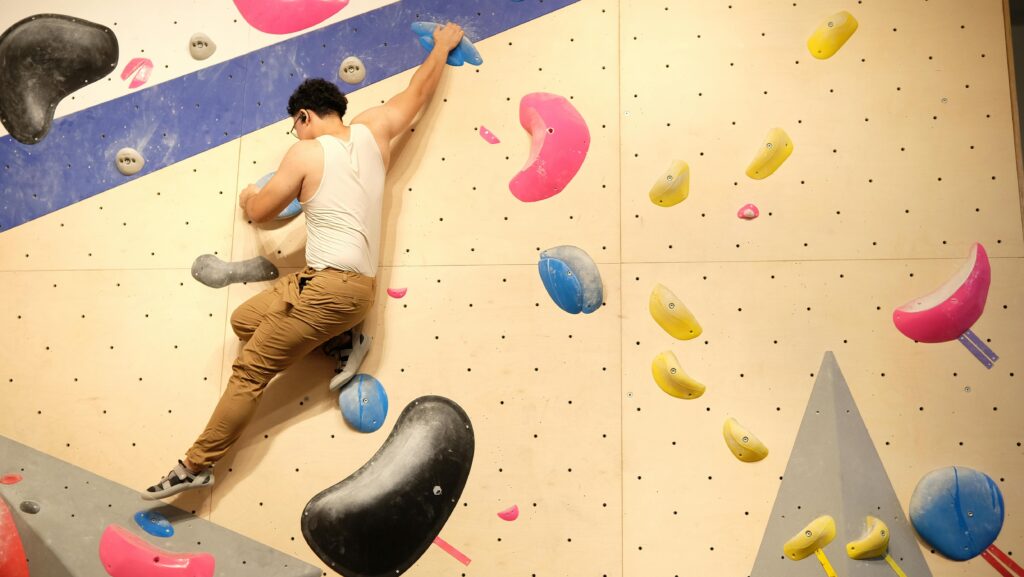 A person bouldering on an indoor climbing wall with colorful holds.