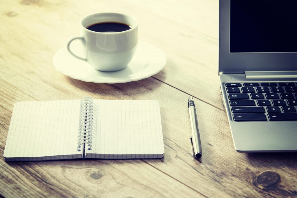 coffee, computer, cup, desk, drink, laptop, coffee cup, notebook, pen, table, wooden table, workspace, work from home