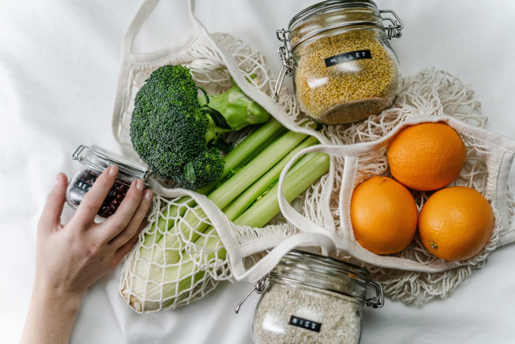 A flat lay of fresh vegetables and grains in reusable bags promoting zero waste and health.