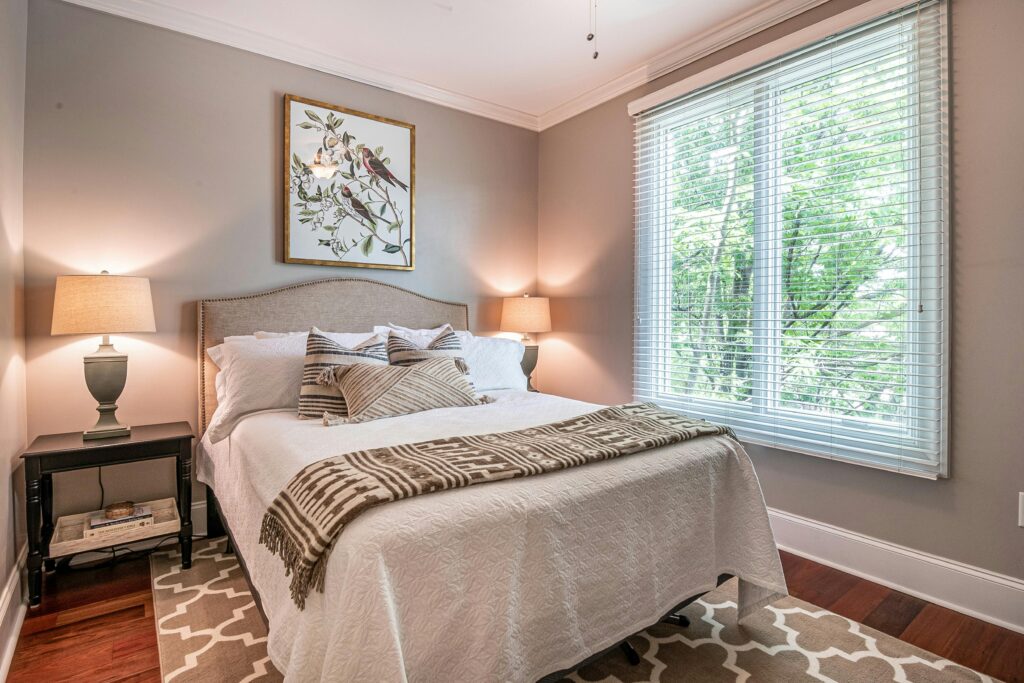 A welcoming bedroom featuring stylish decor, ambient lighting, and a large window view.