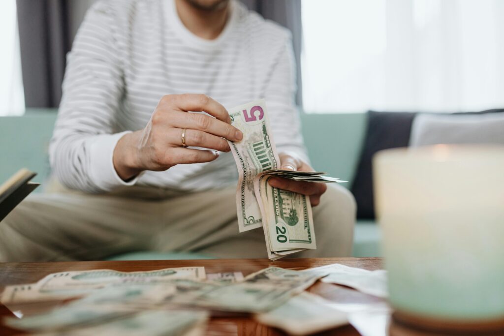 Close-up of hands counting dollar bills indoors, offering a personal finance theme.